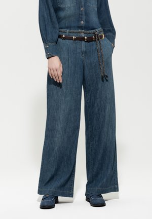 Wide-leg denim pants in dark blue, featuring a textured finish, a braided belt with metal accents, and a relaxed fit at the waist and legs.