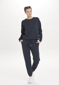 Dunkelblaues Sweatshirt- und Jogginganzug-Set aus weichem Material. Das Sweatshirt hat einen Rundhalsausschnitt und lange Ärmel; die Jogginghose besitzt einen elastischen Bund.