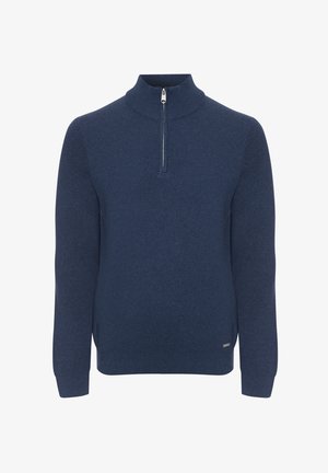 Tmavě modrý svetr se zapínáním na zip u krku, vyrobený z měkkého pleteného materiálu, s dlouhými rukávy a volnějším střihem, s nenápadnou značkovou štítkem na lemu.