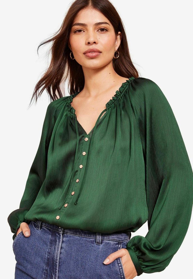 Grüne Seidenbluse mit einem voluminösen Ausschnitt, Knopfleiste und langen Ärmeln. Bemerkenswerte Merkmale sind der sanfte Glanz und die lässige Passform.