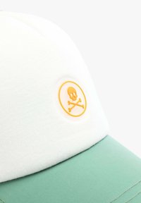 Baseball cap with a white crown and mint green visor. Features a round yellow badge with a skull and crossbones symbol. Smooth texture.