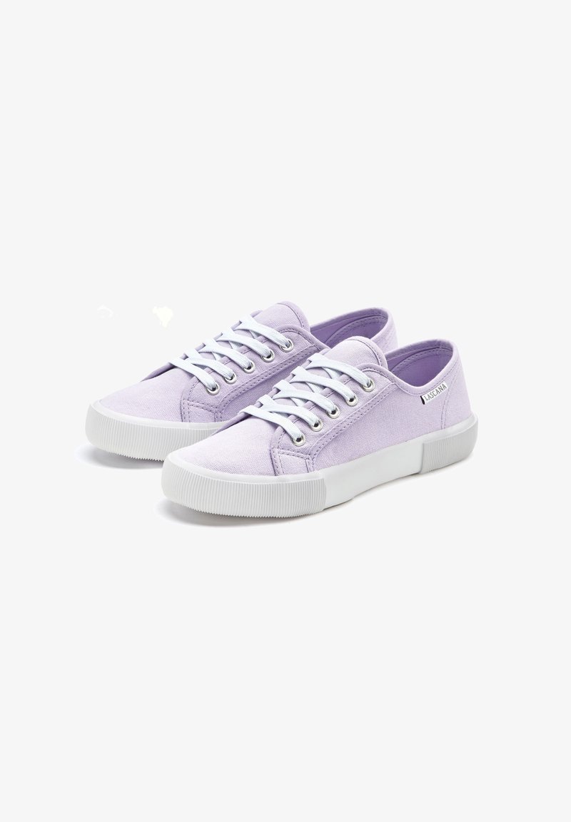 Paire de baskets basses en toile violet clair avec lacets blancs et semelles épaisses en caoutchouc blanc, étiquette de logo latérale visible.