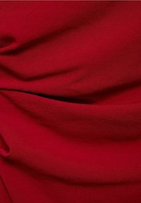 Roter Stoff mit glatter Textur, der weiche Falten und Knicke aufweist, und eine reiche, tiefe Farbe ohne Muster oder Verzierungen zeigt.