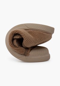 Chaussure slip-on en tissu marron avec un dessus texturé à nervures, un bout arrondi et une semelle en caoutchouc présentant un motif en losange. Pliée en forme compacte.