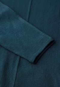 Turkusowy sweter dzianinowy o miękkiej teksturze, z okrągłym dekoltem i długimi rękawami. Materiał prezentuje subtelny gradient kolorów.