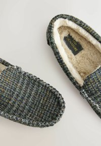 Wollschuhe mit einem strukturierten, mehrfarbigen Äußeren, grauem Rand, weicher Kunstfell-Beschichtung und kontrastierendem Nähten entlang der Sohle.