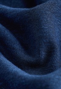 Close-up van zachte, donkerblauwe gebreide stof met gedetailleerde textuur en plooien.