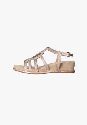 Sandalia de cuña beige con parte superior de varias tiras brillantes y correa ajustable en el tobillo con hebilla dorada, suela plana y soporte trasero cerrado.