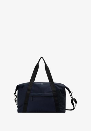Bolsa de lona azul marino hecha de tela duradera, con correas negras, un bolsillo frontal con cremallera y un detalle de logo en el costado. Correa de hombro ajustable.