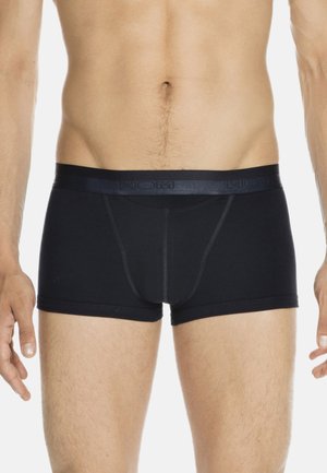 Mandetorso iført sorte tætsiddende boxer briefs med en mærket waistband, stående med afslappede arme langs siderne på en hvid baggrund.