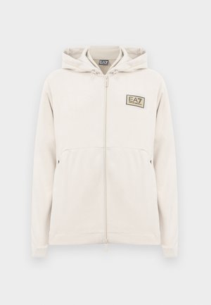 Svetlo bež zip-up kapuca iz mehkega blaga, ki ima kapuco, sprednji žep in oznako logotipa EA7 na levem prsnem delu. Gladka tekstura.