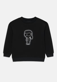 Sweat-shirt noir à col rond, avec un graphique central blanc représentant un personnage en lunettes de soleil et costume. Texture douce, poignets et ourlet côtelés.