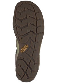 Brown rubber outsole with deep tread patterns and a zigzag design. Features a raised logo in orange. Suitable for traction and durability.
