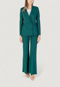 Blazer doppiopetto teal abbinato a pantaloni a gamba larga. Realizzato in tessuto liscio, presenta una vestibilità sartoriale e due tasche frontali.