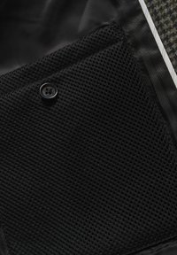 Tasca in rete nera con un bottone, su uno sfondo di rivestimento interno nero liscio. Presenta un sottile accento a righe e un tessuto testurizzato.