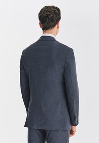 Granatowa, teksturowana marynarka o dopasowanym kroju, z wyciętymi klapami i trzema guzikami. Elegancki i minimalistyczny design.