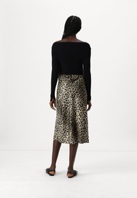 Black long-sleeve top paired with a gold and black leopard-print satin skirt, featuring a flowy silhouette and mid-calf length.