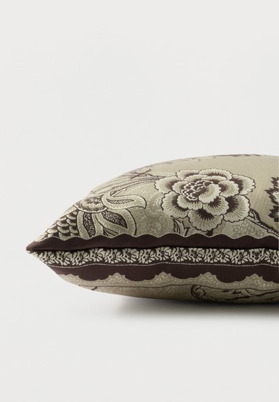 Coussin décoratif rectangulaire avec motif floral beige et marron et bordure ornée complexe sur fond clair.