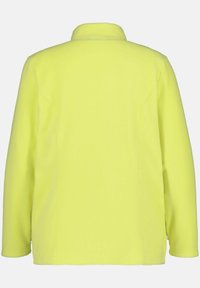 Żółta polarowa kurtka, długie rękawy, kołnierz, gładka tekstura, luźny krój, brak widocznych elementów metalowych lub wzorów, tylko widok z tyłu.