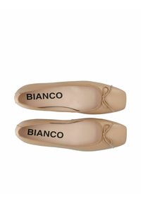 Ballerines beige avec un bout carré et un petit nœud à l'avant. Fabriquées en matériau synthétique lisse. Marquage noir "BIANCO" sur la semelle intérieure.