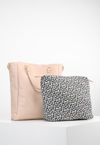 Brązowa torba na ramię z podwójnymi paskami, zestawiona z czarno-białym materiałowym woreczkiem w wzory. Gładka faktura, prosty design i funkcjonalny rozmiar.