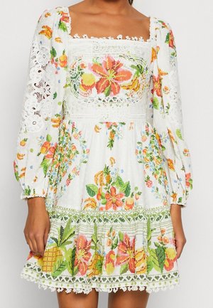 Vestido floral blanco con patrones bordados coloridos; escote cuadrado, mangas largas abullonadas, detalles de encaje y dobladillo en capas con ribete verde.