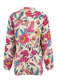 Blusa a stampa floreale con maniche lunghe. Presenta uno sfondo crema, fiori rosa brillante, rossi e turchesi, e un colletto. Texture liscia.