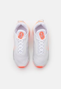 White athletic shoes with a mesh upper, orange accents, and a rounded toe. Features a lace-up design and padded collar for support.