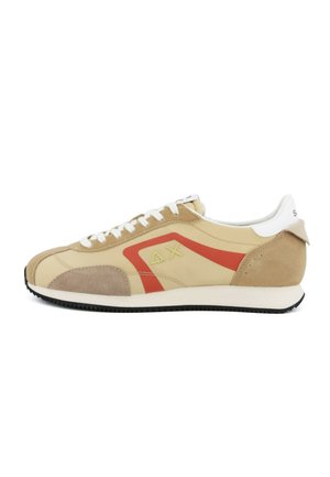 Scarpa da ginnastica beige e marrone chiaro con lacci bianchi, striscia geometrica rossa, simboli delta e X gialli sul lato, linguetta bianca sul tallone e suola nera.