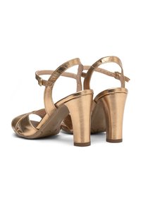 Goldene metallische Absatzsandalen mit Knöchelriemen, offenes Zehendesign, strukturierte Oberfläche und ein dicker Absatz, gezeigt in Rückansicht und Seitenansicht.