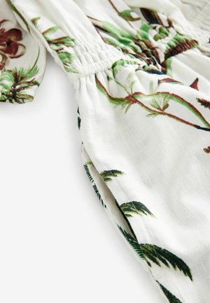 Tessuto bianco con foglie verdi e motivi floreali, dotato di dettagli arricciati elasticizzati e una texture liscia.