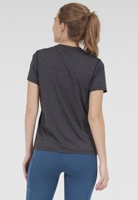 Kolkgray t-shirt med kort ärm och rund halsringning, tillverkad av lätt, texturerad tyg. Kombinerad med blåa träningsleggings.