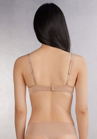 Nackter, kabelloser BH mit verstellbaren Trägern, nahtlosem Design und Haken-und-Ösen-Verschluss. Weicher Stoff mit einer glatten Textur auf der Rückseite.