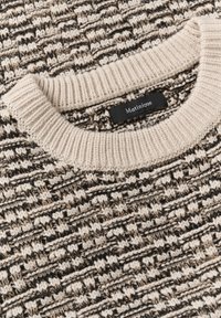 Pulover tricotat cu un model texturat în crem, negru și taupe. Guler rotund cu nervuri și eticheta "Matinique" în interior.