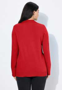 Cardigan rosso lavorato a maglia con maniche lunghe, colletto e una vestibilità leggermente oversize. Presenta dettagli testurizzati all'orlo e ai polsini.