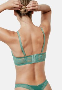 Soutien-gorge en dentelle teal avec des bretelles ajustables et une fermeture à crochets. Un délicat motif floral et un ourlet festonné accentuent son design élégant.