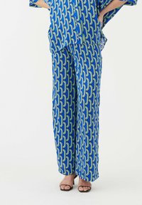 Ensemble en deux pièces composé d'un haut ample et d'un pantalon large. Fabriqué en tissu léger avec un motif géométrique vibrant en bleu, vert et blanc.