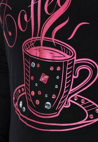 Czarna tkanina zdobiona różowym motywem filiżanki kawy z parą, ozdobiona błyszczącymi różowymi i przezroczystymi kamieniami dla dodatkowej faktury i detali.