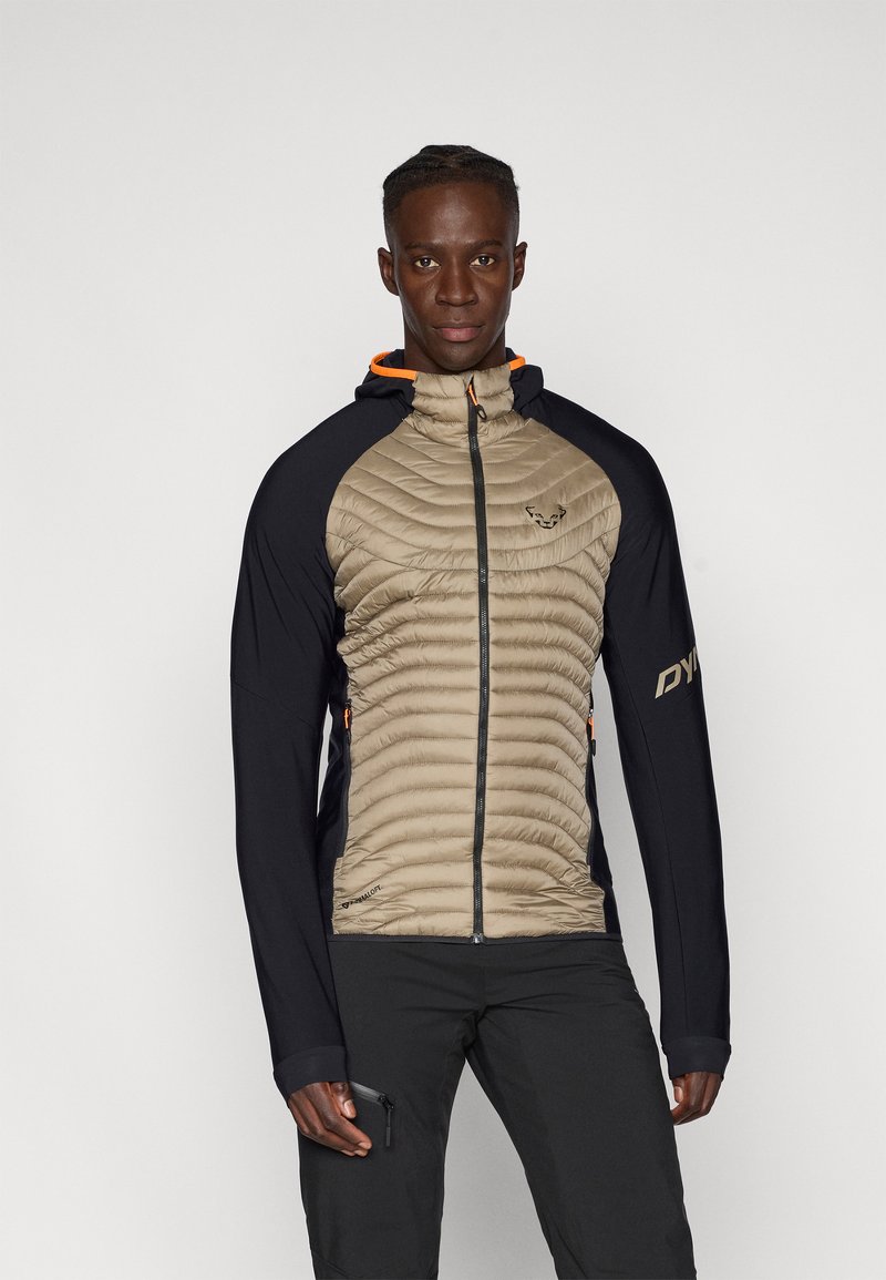 Veste isolante avec un corps matelassé beige, des manches noires et un accent orange sur la capuche. Comprend une fermeture éclair à l'avant et des détails de logo.