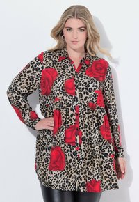 Camicia a maniche lunghe con stampa leopardata e grandi rose rosse, chiusura con bottoni e vita arricciata per una vestibilità rilassata.