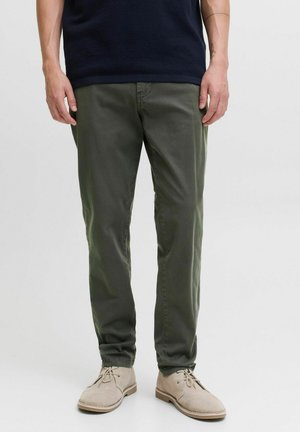 Olive green cotton chinos with a slim fit, featuring side pockets and back pockets, paired with light beige suede shoes.