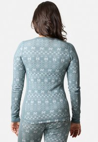 Langsleeve shirt in lichtblauw met witte sneeuwvlokken- en diamantpatronen. Zachte, rekbare stof; de getailleerde pasvorm accentueert de lichaamsvorm.
