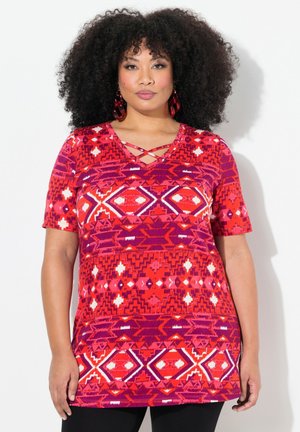 Tunique à manches courtes en rouge et violet avec des motifs géométriques, dotée d'un décolleté en V avec des détails entrecroisés et une coupe décontractée.