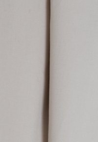 Tessuto beige chiaro con una texture liscia, caratterizzato da una leggera rigatura. Il materiale appare leggermente elasticizzato e si drappeggia delicatamente.