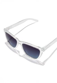 Prozorna acetatna sončna očala s prelivajočimi se lečami od temno do svetlomodre barve; okvir z ostro obliko; gladke teksture; elegantna prozorna stranica.