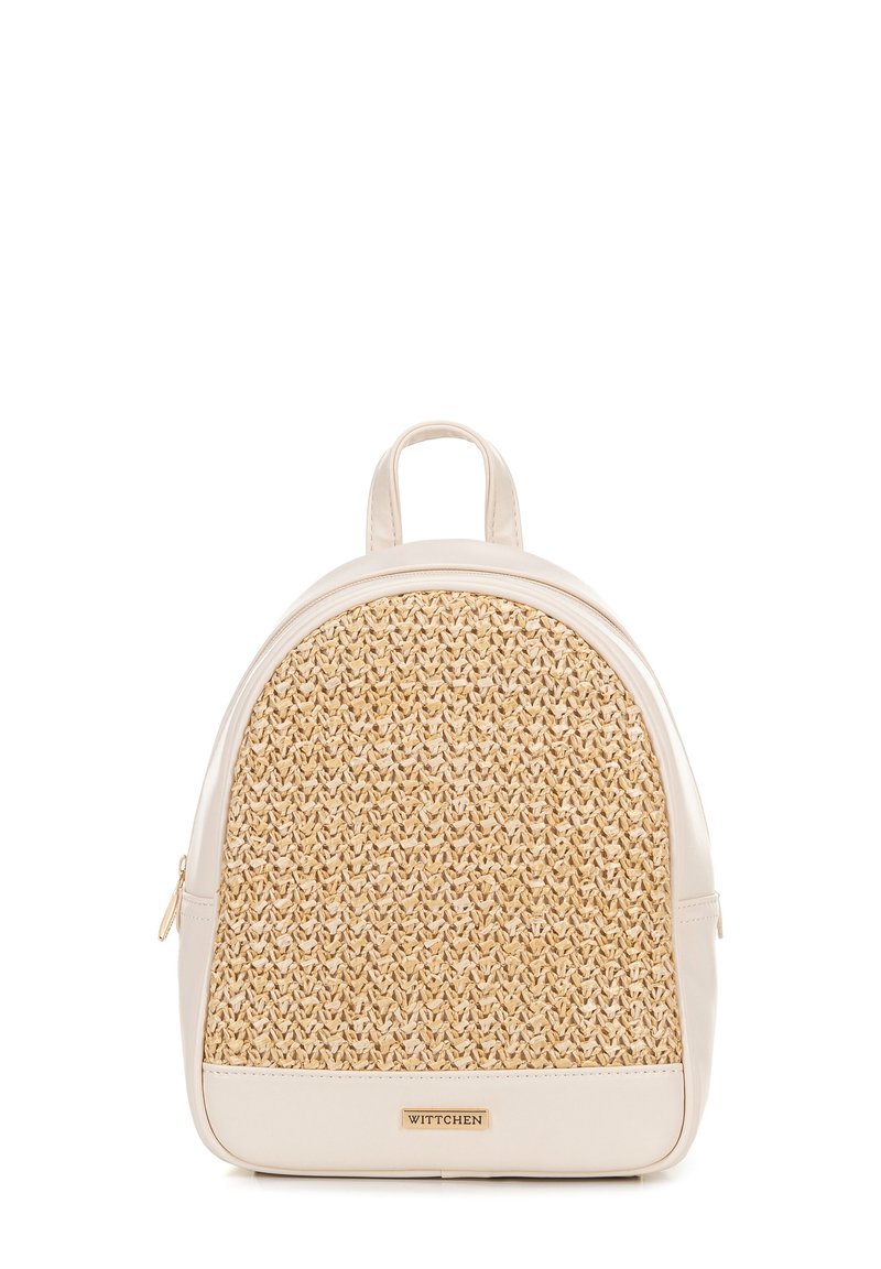 Mochila tejida beige con forma redondeada, detalles de cuero y un asa en la parte superior. Presenta una superficie texturizada y un detalle de logotipo metálico.