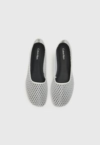 Scarpe slip-on grigie in rete con un motivo a diamante, punte arrotondate e soletti neri con logo bianco del marchio. Design leggero e flessibile.