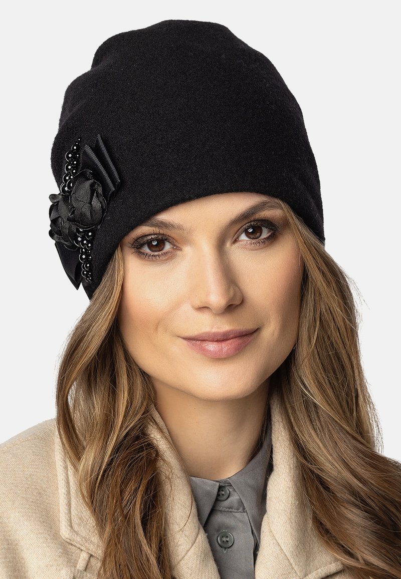Gorro de lana negro con acento de tela floral, superficie texturizada y cuentas negras decorativas. Diseño ajustado para brindar calidez y estilo.