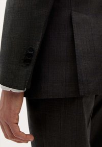 Chaqueta de traje gris oscuro texturizada con un sutil patrón de cuadros. Cuenta con tres botones negros en los puños y un diseño con pliegues en el dobladillo.