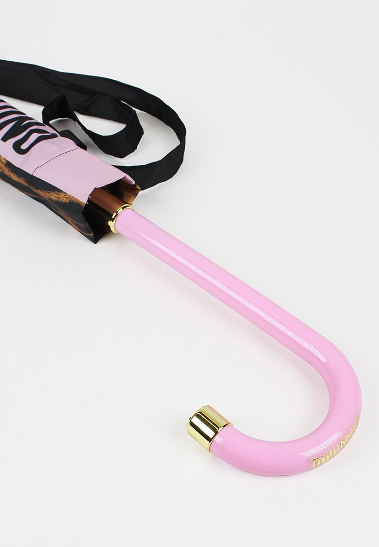 Un paraguas rosa con un mango brillante, que presenta un acento dorado. La cubierta está parcialmente cubierta con una funda de tela negra que muestra un patrón.